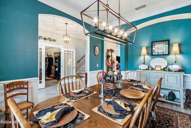 dining area featuring crown molding, hardwood / wood-style floors, and a notable chandelier