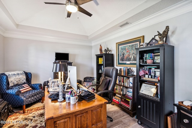 office with ceiling fan, a raised ceiling, light wood-type flooring, and crown molding