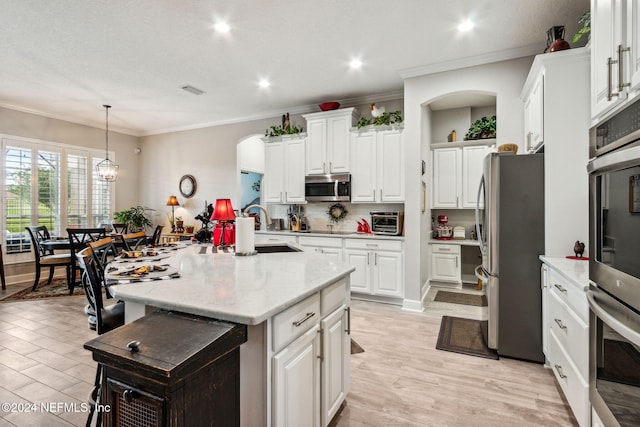 kitchen featuring a center island with sink, white cabinets, and stainless steel appliances