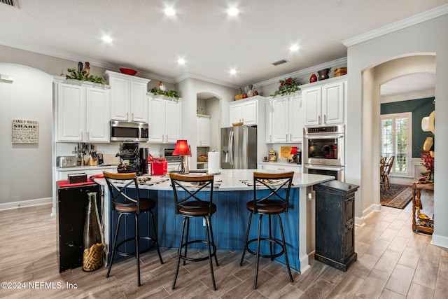 kitchen with light wood-type flooring, stainless steel appliances, white cabinetry, and a large island