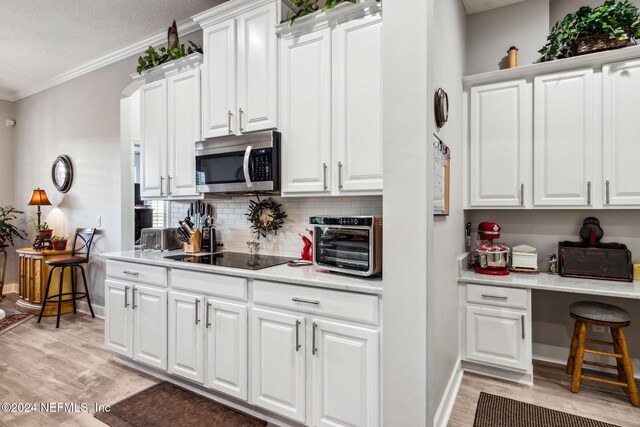 kitchen with white cabinets, crown molding, light wood-type flooring, a textured ceiling, and black electric cooktop