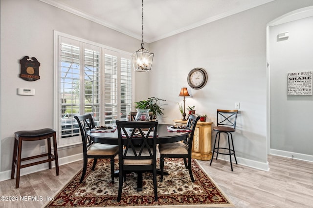 dining space with light hardwood / wood-style floors, an inviting chandelier, and crown molding