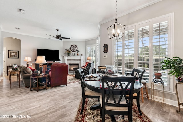 dining area featuring plenty of natural light, light wood-type flooring, crown molding, and ceiling fan with notable chandelier