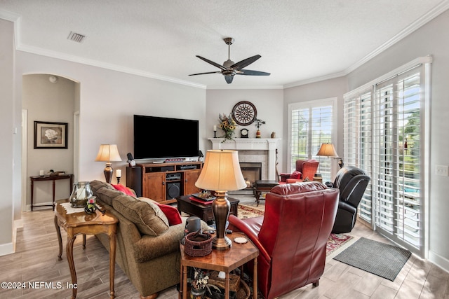 living room featuring a textured ceiling, light hardwood / wood-style flooring, ceiling fan, and ornamental molding