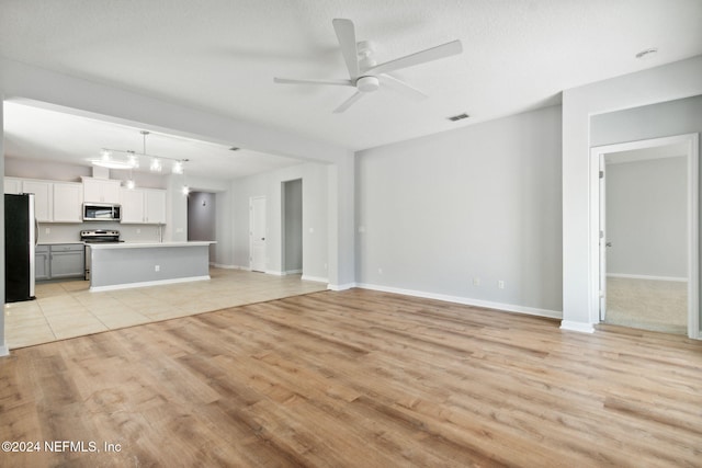 unfurnished living room with ceiling fan, a textured ceiling, and light wood-type flooring