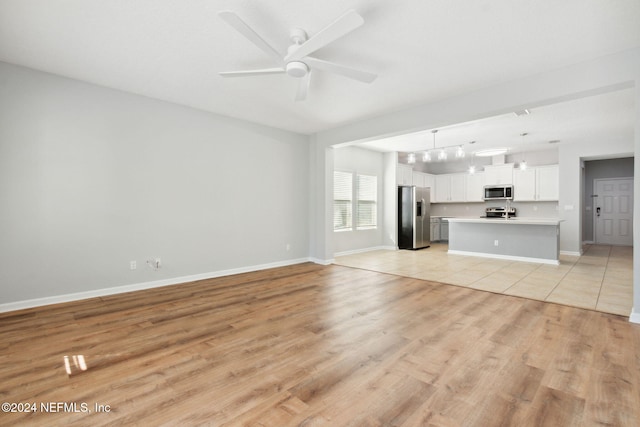 unfurnished living room featuring ceiling fan and light hardwood / wood-style flooring