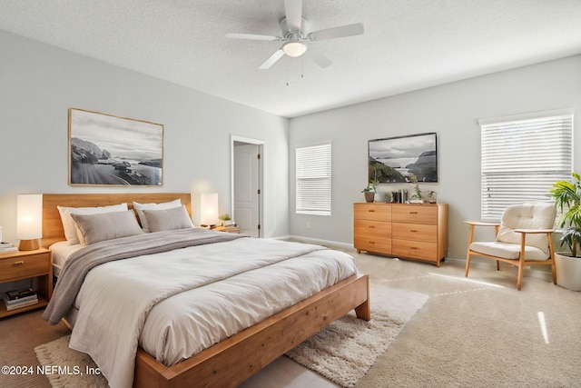 carpeted bedroom featuring ceiling fan and a textured ceiling