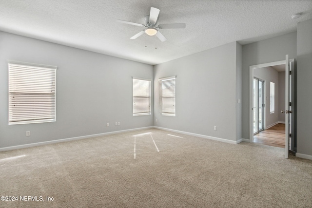 carpeted spare room featuring ceiling fan and a textured ceiling