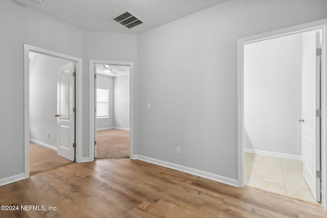 empty room featuring ceiling fan, light hardwood / wood-style floors, and a textured ceiling