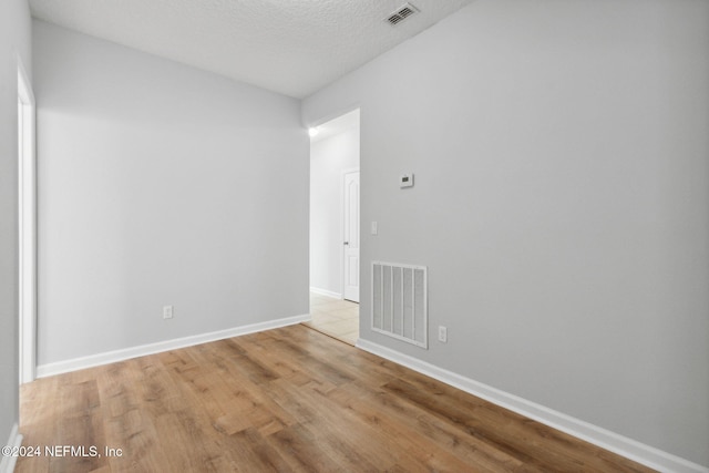 unfurnished room with a textured ceiling and light hardwood / wood-style flooring