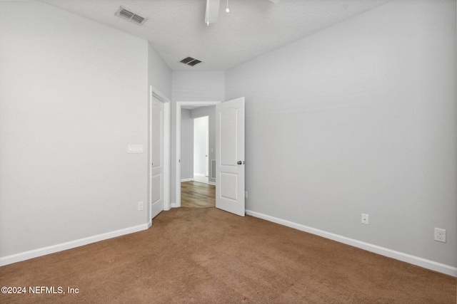 carpeted empty room featuring a textured ceiling