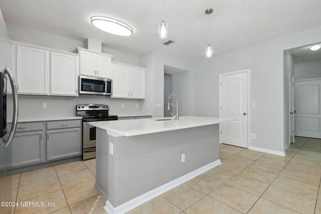 kitchen featuring sink, decorative light fixtures, a center island with sink, white cabinets, and appliances with stainless steel finishes