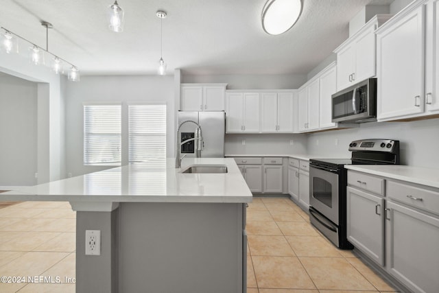 kitchen featuring a center island with sink, sink, hanging light fixtures, light tile patterned floors, and appliances with stainless steel finishes