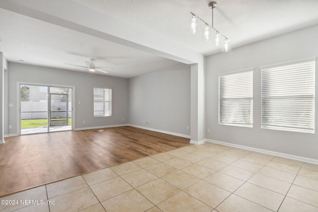 empty room with ceiling fan, light hardwood / wood-style floors, and a textured ceiling