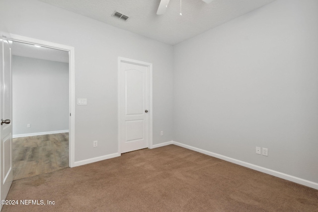 unfurnished bedroom with a textured ceiling, carpet floors, and ceiling fan