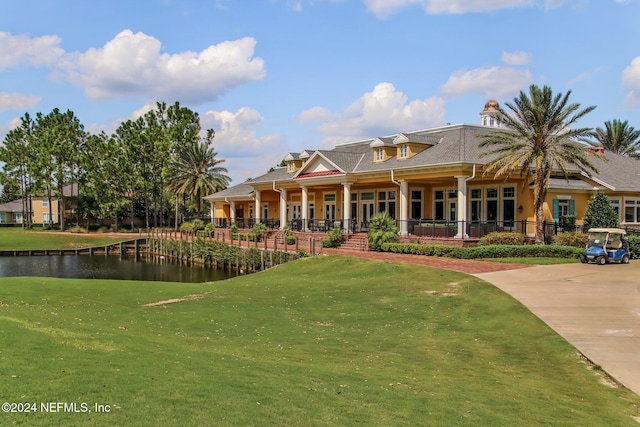 back of property with covered porch, a yard, and a water view