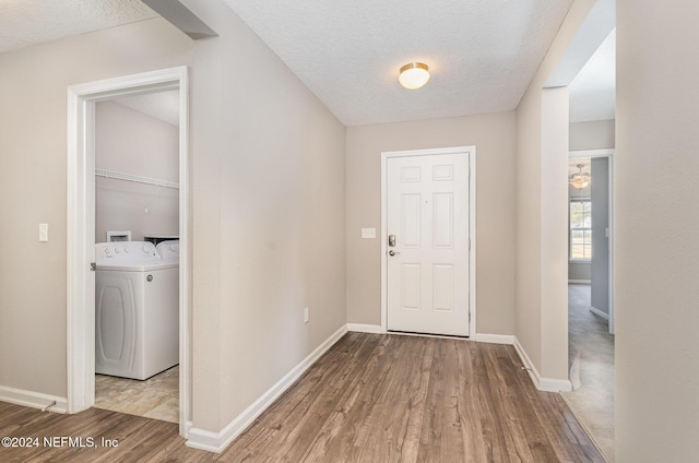 foyer entrance featuring separate washer and dryer, a textured ceiling, and hardwood / wood-style flooring