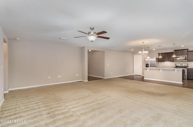 unfurnished living room with ceiling fan with notable chandelier, light colored carpet, and a textured ceiling