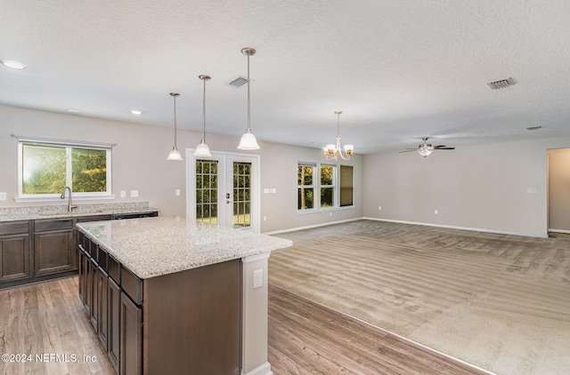 kitchen featuring dark brown cabinetry, french doors, sink, hanging light fixtures, and light hardwood / wood-style flooring