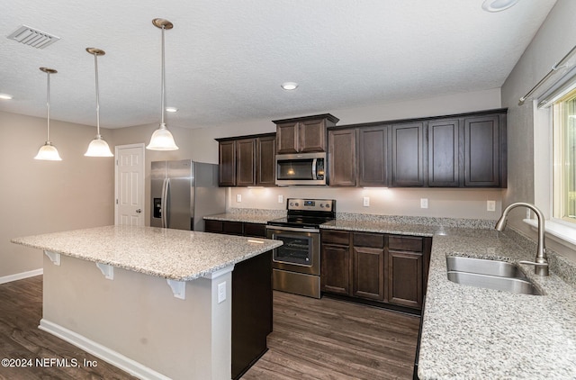 kitchen with pendant lighting, dark hardwood / wood-style floors, sink, and stainless steel appliances