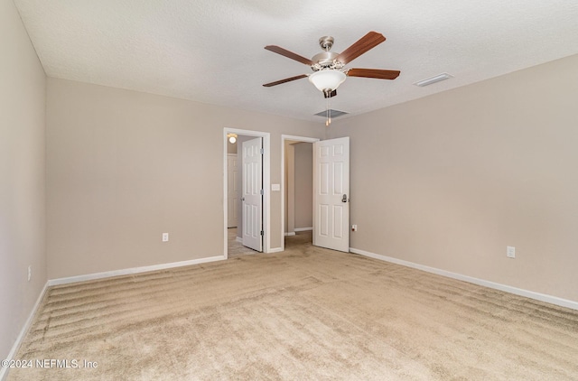 spare room with a textured ceiling, light colored carpet, and ceiling fan