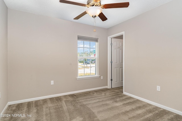 spare room with ceiling fan, light colored carpet, and a textured ceiling