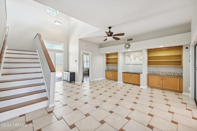 unfurnished living room featuring ceiling fan and built in features