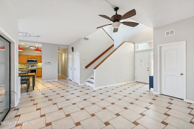 unfurnished living room with ceiling fan and a textured ceiling