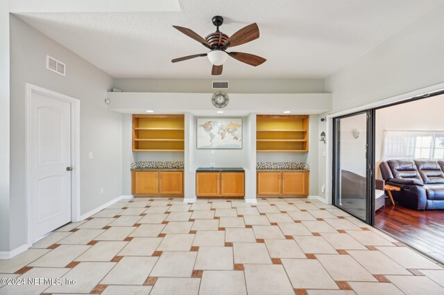 interior space featuring built in shelves, light wood-type flooring, and ceiling fan