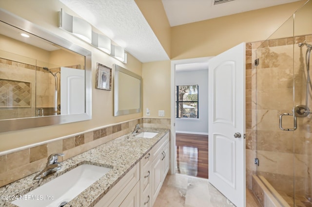 bathroom featuring hardwood / wood-style flooring, vanity, a shower with shower door, and a textured ceiling