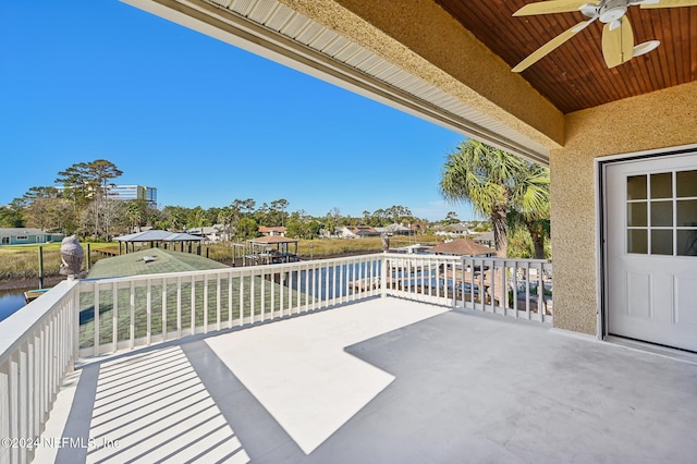 view of patio featuring ceiling fan, a balcony, and a water view