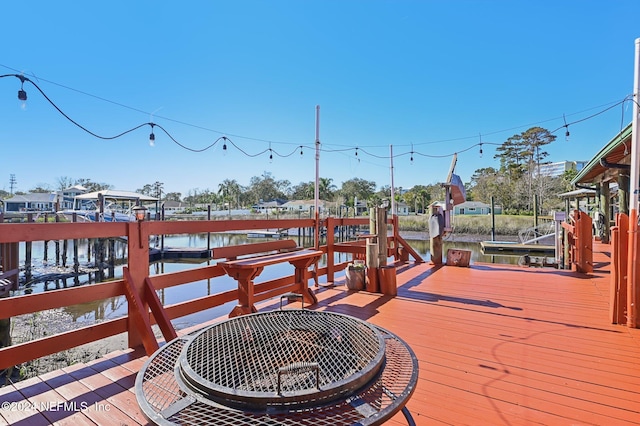 wooden deck with a fire pit, a water view, and a dock