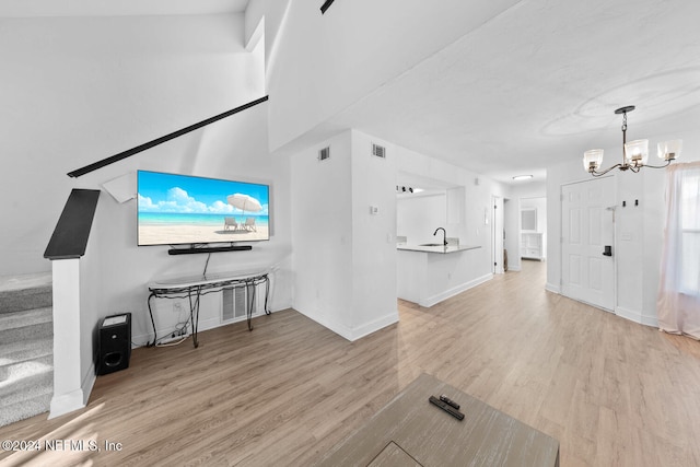 living room featuring sink, an inviting chandelier, and light wood-type flooring