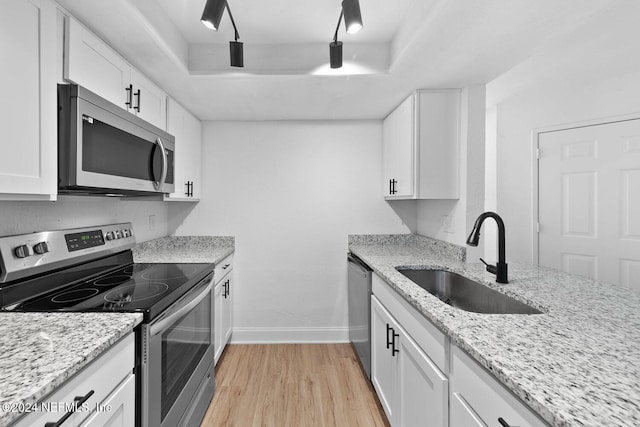 kitchen featuring light stone countertops, appliances with stainless steel finishes, sink, light hardwood / wood-style flooring, and white cabinets