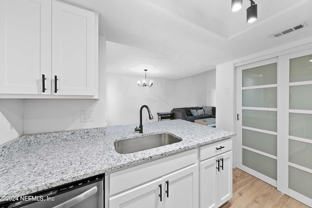 kitchen featuring light stone countertops, sink, stainless steel dishwasher, light hardwood / wood-style floors, and white cabinets