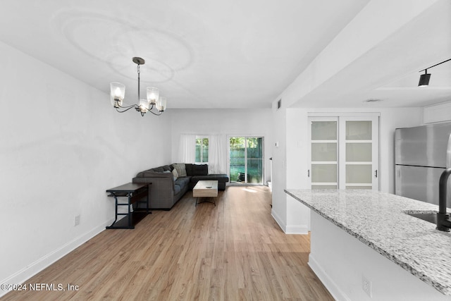 interior space with a notable chandelier, sink, and light hardwood / wood-style flooring