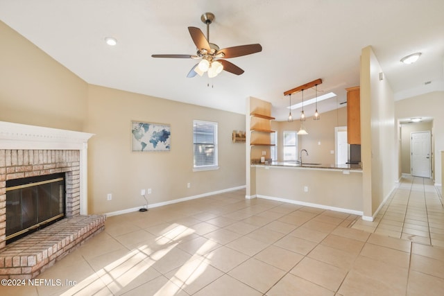 unfurnished living room featuring ceiling fan, sink, vaulted ceiling, a fireplace, and light tile patterned floors