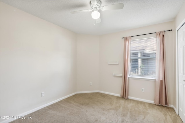 empty room with a textured ceiling, ceiling fan, and light carpet