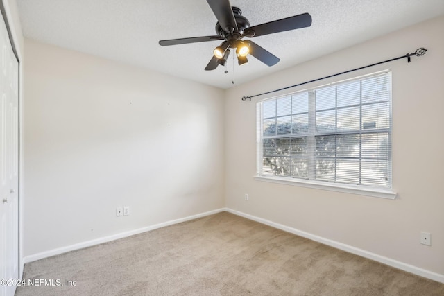 unfurnished bedroom with a textured ceiling, ceiling fan, light carpet, and a closet