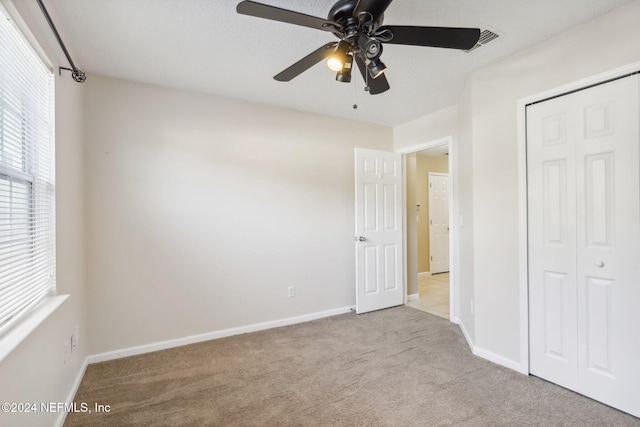 unfurnished bedroom featuring light carpet, a closet, and ceiling fan