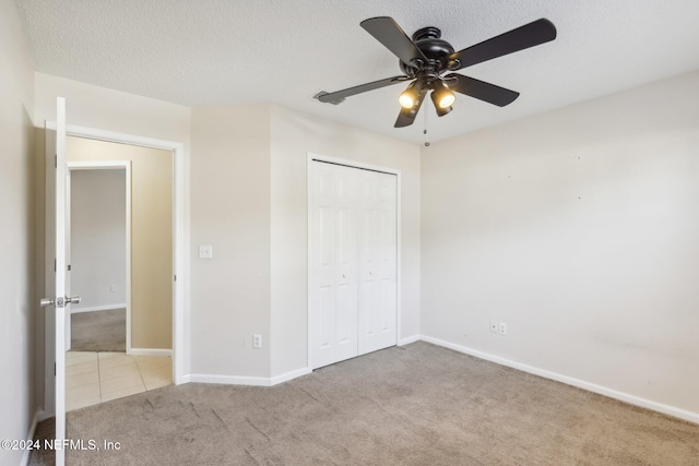 unfurnished bedroom with light carpet, a textured ceiling, a closet, and ceiling fan