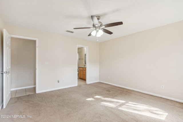 unfurnished bedroom featuring light colored carpet, ceiling fan, and ensuite bathroom