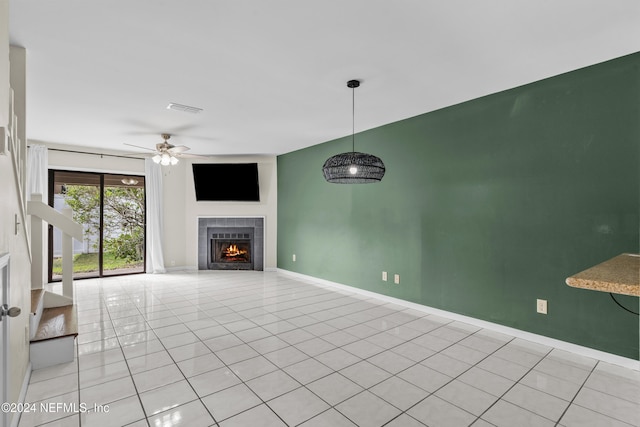 unfurnished living room with ceiling fan, a fireplace, and light tile patterned floors