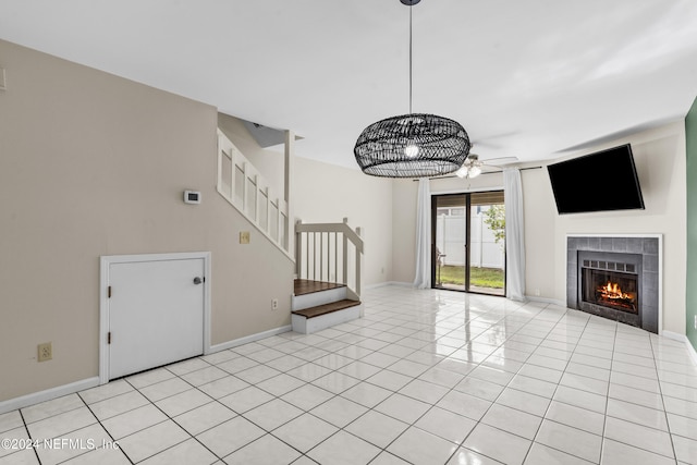 unfurnished living room with ceiling fan, light tile patterned floors, and a tiled fireplace