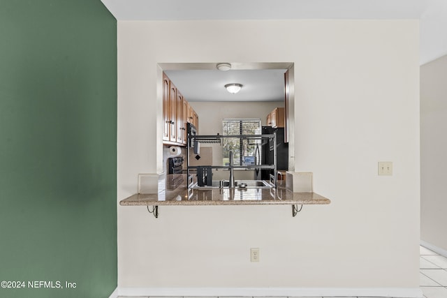 kitchen with stone counters, a kitchen bar, kitchen peninsula, and light tile patterned floors