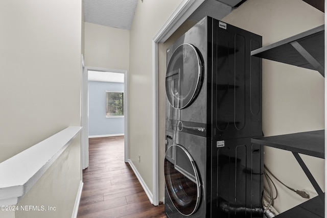 washroom featuring a textured ceiling, dark hardwood / wood-style flooring, and stacked washer / drying machine