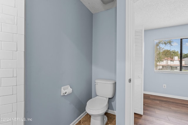 bathroom with hardwood / wood-style floors, a textured ceiling, and toilet