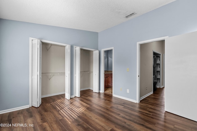 unfurnished bedroom with vaulted ceiling, ensuite bath, dark hardwood / wood-style flooring, and a textured ceiling