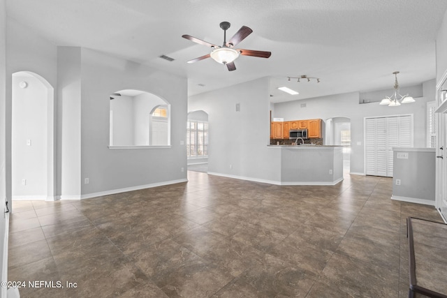 unfurnished living room featuring a textured ceiling and ceiling fan with notable chandelier