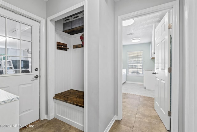 mudroom with light tile patterned floors and a textured ceiling